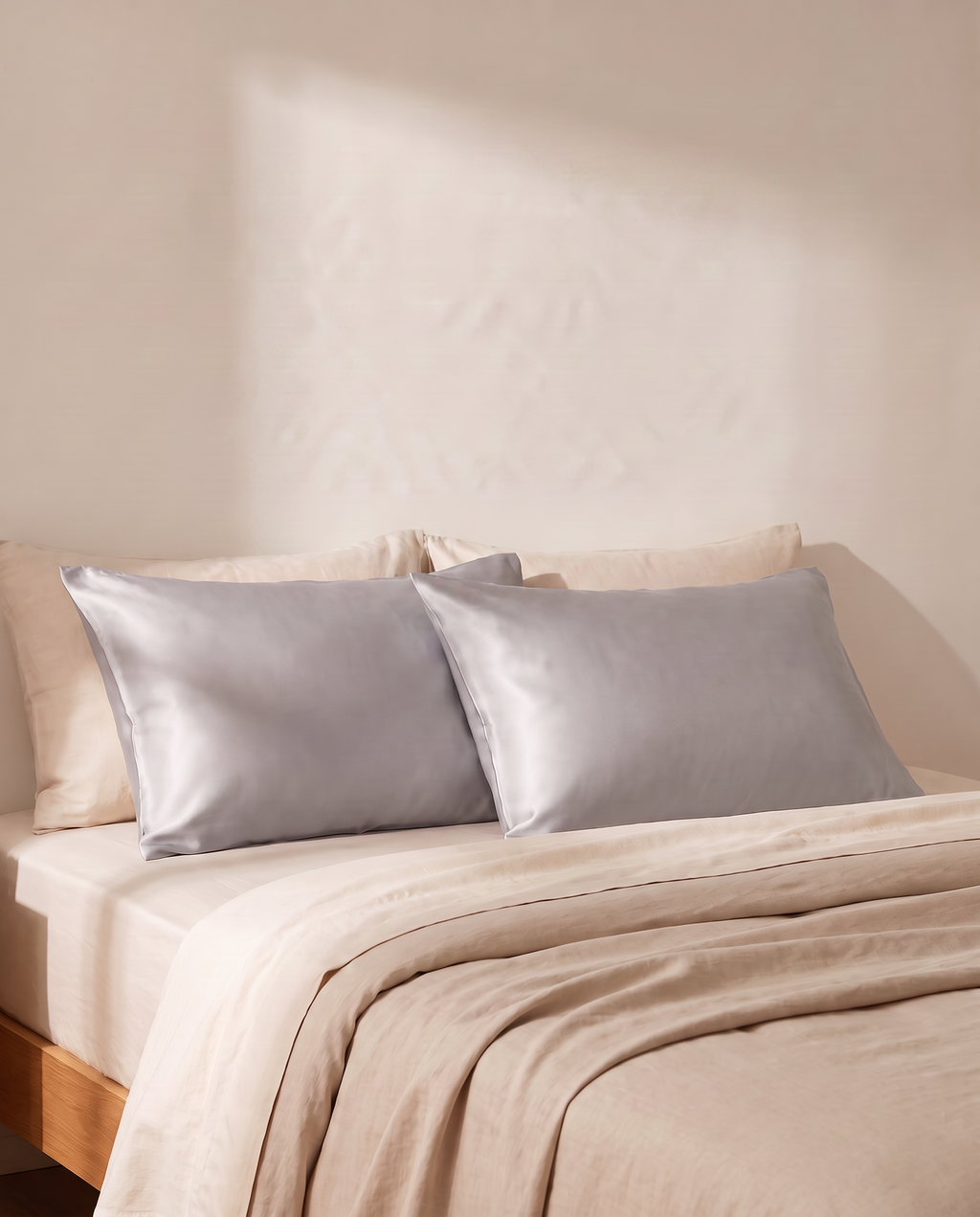 Lullia grey satin cooling pillowcases on an oat-linen bed in soft morning light